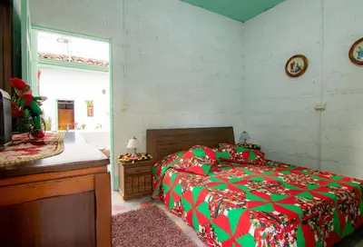 a bedroom with a bed with a red and green blanket at CASA DUQUE JARDIN in Jardin