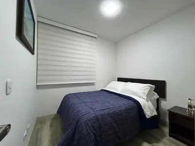 a bedroom with a bed with a blue blanket and a window at Apartamento frente a Mallplaza in Manizales