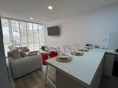 a kitchen and living room with a table and a couch at Apartamento frente a Mallplaza in Manizales