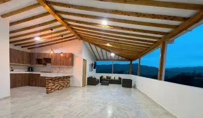 an open kitchen and living room with wooden ceilings at Cómoda casa con espectacular vista a la piedra y embalse in Guatapé