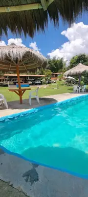 a swimming pool with a straw umbrella and chairs and tables at Cabaña rodeada de naturaleza in Cocorná