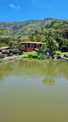 a house sitting next to a large body of water at Cabaña rodeada de naturaleza in Cocorná