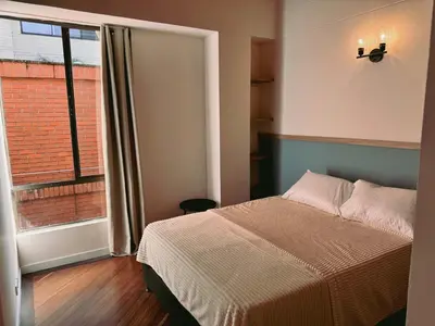 a bedroom with a bed and a large window at Seijakumanila in Medellín