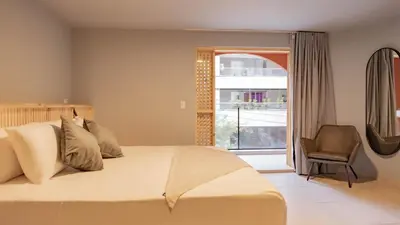 a bedroom with a bed and a chair and a window at Leviu by Bernalo Hotels in Medellín