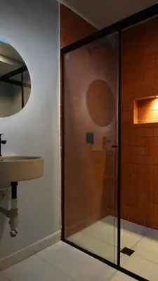 a glass shower in a bathroom with a sink at Leviu by Bernalo Hotels in Medellín