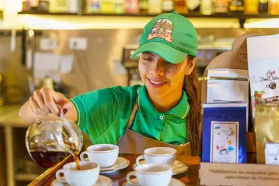 a woman in a kitchen pouring coffee into cups at Hotel Campestre - CIUDADELA EL ARTESANO in Carolina del Principe