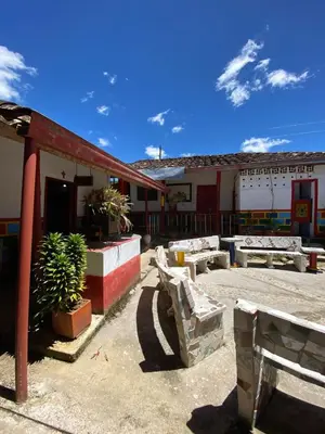 a building with tables and benches in a courtyard at Hotel Campestre - CIUDADELA EL ARTESANO in Carolina del Principe