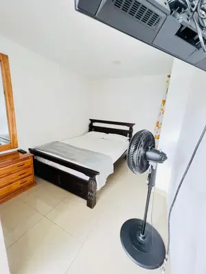 a room with a bed and a desk with a fan at The Best Corner in San Rafael