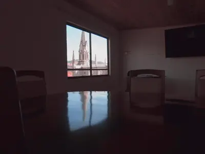a dark room with a window and a view of a church at Hotel Casita de Belén in Sonsón