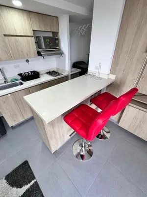 a kitchen with a white counter and red chairs at 1705 Beautiful apartament, total view of the city in Medellín