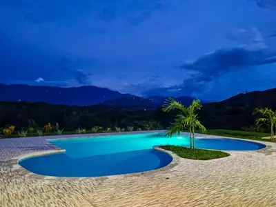 a swimming pool with blue water and palm trees at Finca Luz de Luna in Santa Fe de Antioquia