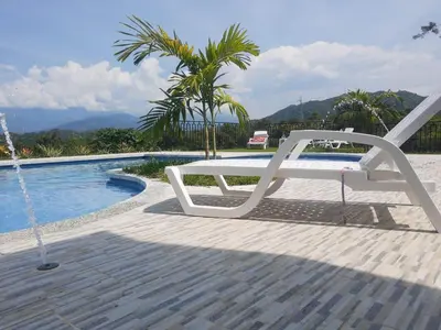 a white bench sitting next to a swimming pool at Finca Luz de Luna in Santa Fe de Antioquia