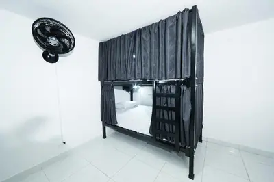 a small bed in a room with black curtains at Hostal Casa Host 72 in Medellín