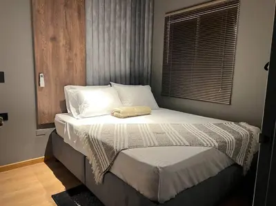 a bedroom with a bed with white sheets and a window at POBLADO PARK MANILA in Medellín