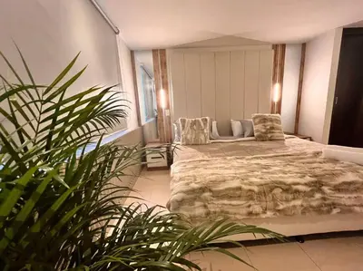 a bedroom with a bed and a chair and a plant at POBLADO PARK LUXURY APARTMENT's in Medellín