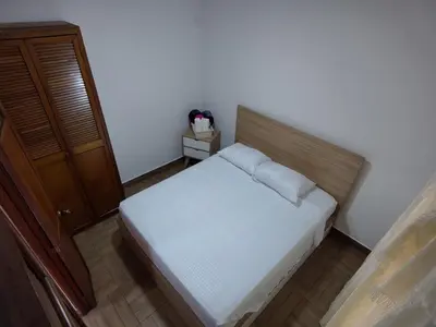 a small bedroom with a white bed with a wooden headboard at Casa primer piso Laureles, Estadio, UPB, la 70 in Medellín