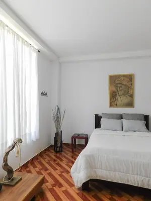 a white bedroom with a bed and a table at Hostal Santa Teresita in La Merced