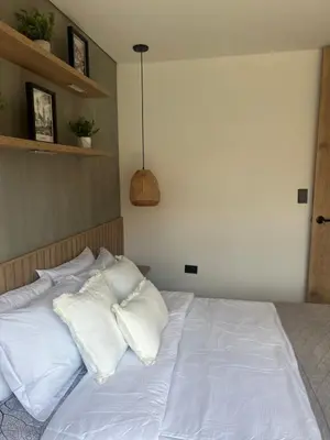 a bed with white sheets and pillows on it at Casa Berlín, Lake Access in Guatapé