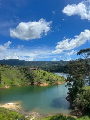 a lake in the middle of a field with a blue sky at Casa Berlín, Lake Access in Guatapé