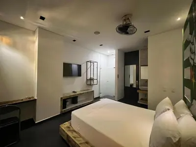a bedroom with a large white bed and a kitchen at Hotel Medellin Arte in Medellín
