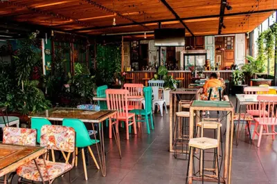 a restaurant with tables and chairs and a person sitting at it at Hotel Medellin Arte in Medellín