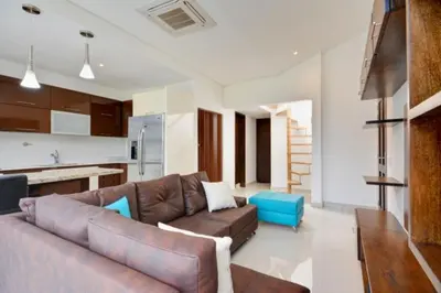 a living room with a brown leather couch and a kitchen at Apartamento Lleras AC Hot Tub in Medellín