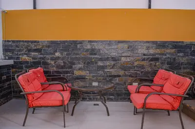 three red chairs and a table in front of a brick wall at Apartamento Lleras AC Hot Tub in Medellín