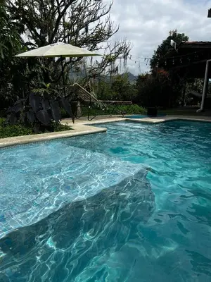 a large pool of blue water with an umbrella at Casa Nutabe - Casa de Campo en Girardota cerca a Medellín in Girardota