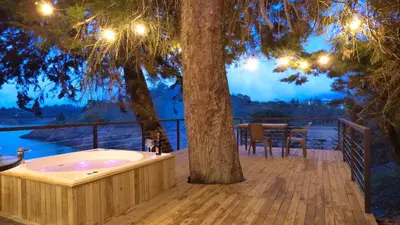 a jacuzzi tub sitting on a deck next to a tree at Tree House, Cabaña privada con Jacuzzi y canoa in Guatapé