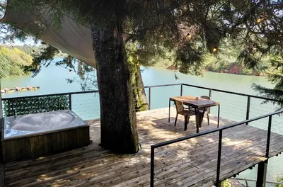 a deck with a tree and a table and a tub at Tree House, Cabaña privada con Jacuzzi y canoa in Guatapé