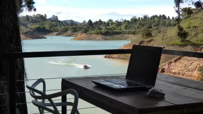 a laptop computer sitting on a table next to a river at Tree House, Cabaña privada con Jacuzzi y canoa in Guatapé