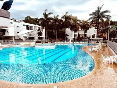 a large blue swimming pool with chairs and palm trees at Apartasol Santa Fe de Antioquia in Santa Fe de Antioquia