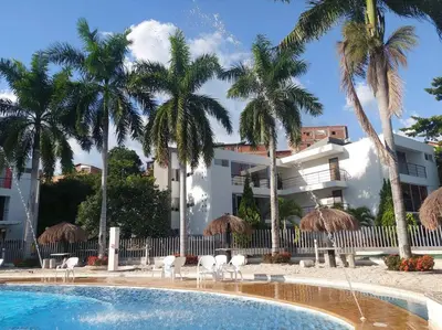 a pool with chairs and umbrellas in front of a building at Apartasol Santa Fe de Antioquia in Santa Fe de Antioquia
