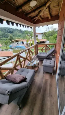 a room with couches and a balcony with a view at Cabaña del lago in Cocorná