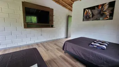 a bedroom with a bed and a flat screen tv at Cabaña del lago in Cocorná