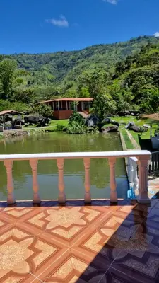 a balcony with a view of a house and a pond at Cabaña vacacinal in Cocorná