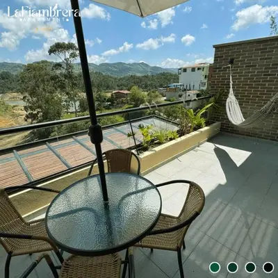 a glass table and chairs on a balcony with an umbrella at Nuevo apto con acceso al embalse en Guatapé in Guatapé