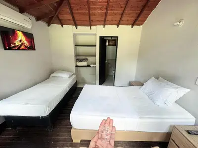 two beds in a room with a persons feet on the floor at Hotel Aero Santa Fe in Santa Fe de Antioquia