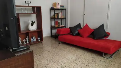 a living room with a red couch and a tv at Casa en Laureles Ideal para Familias in Medellín
