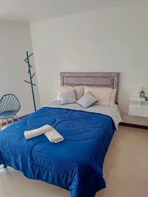 a bed with a blue blanket and two towels on it at Apartamento Duplex en ubicacion privilegiada in Manizales