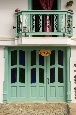 a green garage door with a balcony on top at Habitación La Amelia in Jericó
