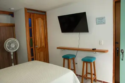 a bedroom with a bed and two stools and a television at Habitación La Amelia in Jericó