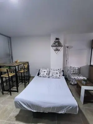 a bedroom with a large white bed and a table at Apartaestudio completo en Itagüí - Shalom - 501 in Itagüí