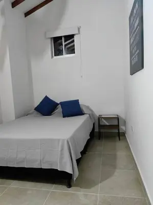 a bedroom with a bed with blue pillows and a window at Apartaestudio completo en Itagüí - Shalom - 501 in Itagüí