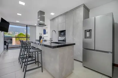a kitchen with a counter with stools and a refrigerator at Medellin-Cerca al Poblado-201 in Medellín