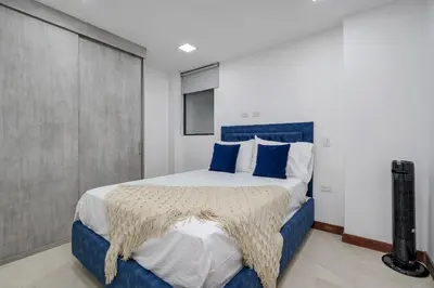 a bedroom with a large bed with blue pillows at MEDELLIN- Cerca al Poblado - 301 in Medellín
