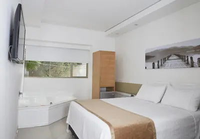 a white bedroom with a bed and a bath tub at Hotel Zona A in Medellín