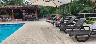 a row of chairs and an umbrella next to a pool at Hotel Parador del Gitano in Doradal