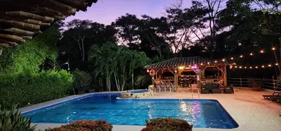 a swimming pool with a gazebo in a backyard at night at Hotel Parador del Gitano in Doradal
