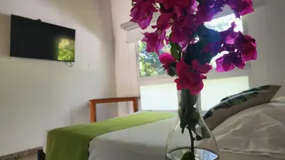 a vase with purple flowers on a table next to a bed at Hotel Parador del Gitano in Doradal